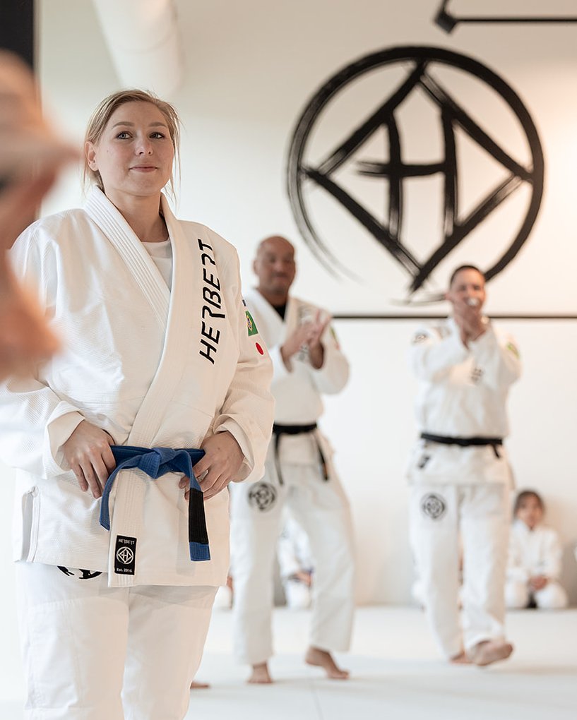 Jiu jitsu banden: volgorde en betekenis (BJJ-bandensysteem) 1 Kersverse blauwe band wordt gevierd tijdens een BJJ-bandenpromotie bij Sportschool Herbert in Ede