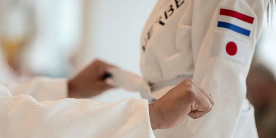 Hoe werkt het Judo Banden en Slippen Systeem? 1 Kinderen tonen hun judoband tijdens de training in Ede