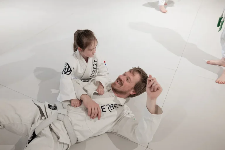 Jong meisje oefent een houdgreep met de coach tijdens Kids Judo in de judozaal van Sportschool Herbert in Ede