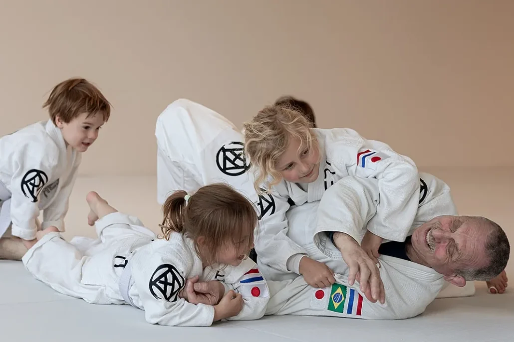 Tuimel Judo in de nieuwe judozaal van Sportschool Herbert in Ede: kleuters stoeien lachend met de docent op de witte mat