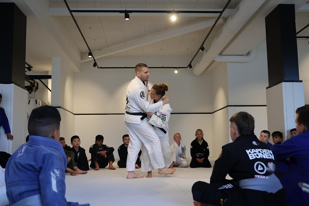 Docent van Sportschool Herbert demonstreert een judotechniek voor een kring kinderen tijdens een vechtsportles in Ede