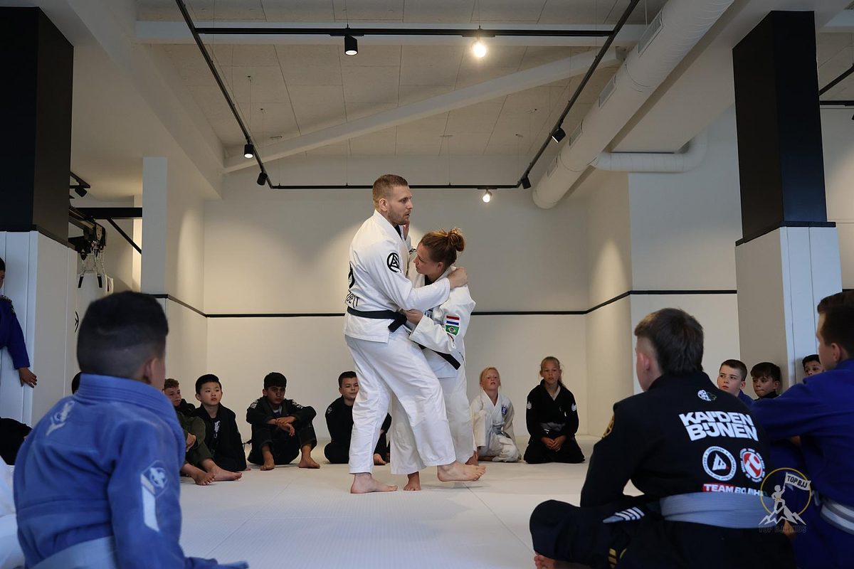 Weerbaarheidstraining: wat is het en wat heb je eraan? 1 Weerbaarheidstraining bij Sportschool Herbert in Ede: docente demonstreert een judotechniek voor een kring kinderen